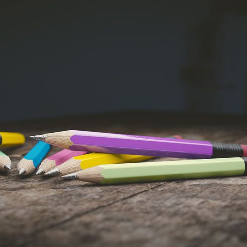 Buntstifte in verschiedenen Farben auf einem Holztisch mit dunklem Hintergrund